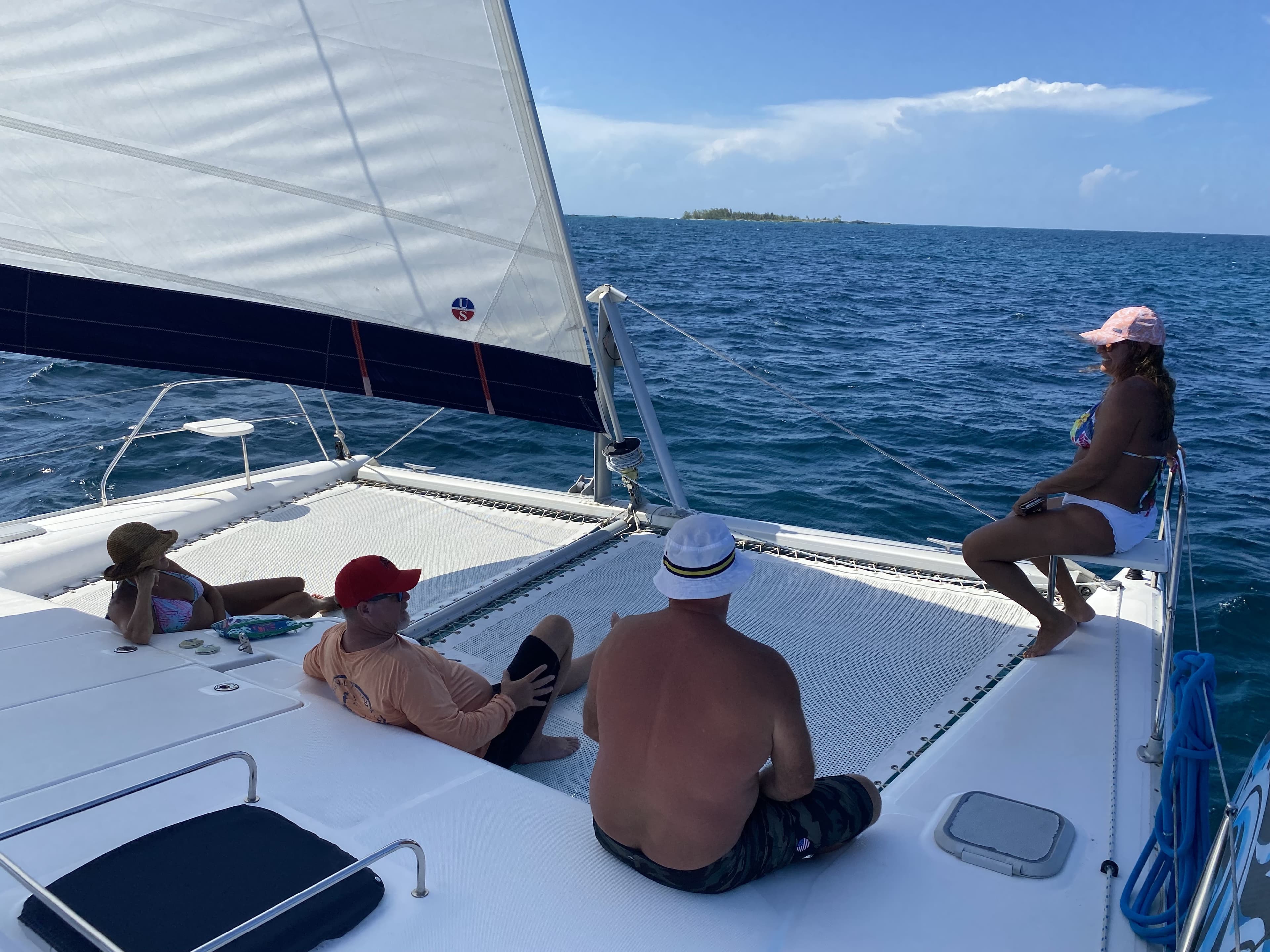 Guests relaxing on the bow of a Surfnsail catamaran under sail